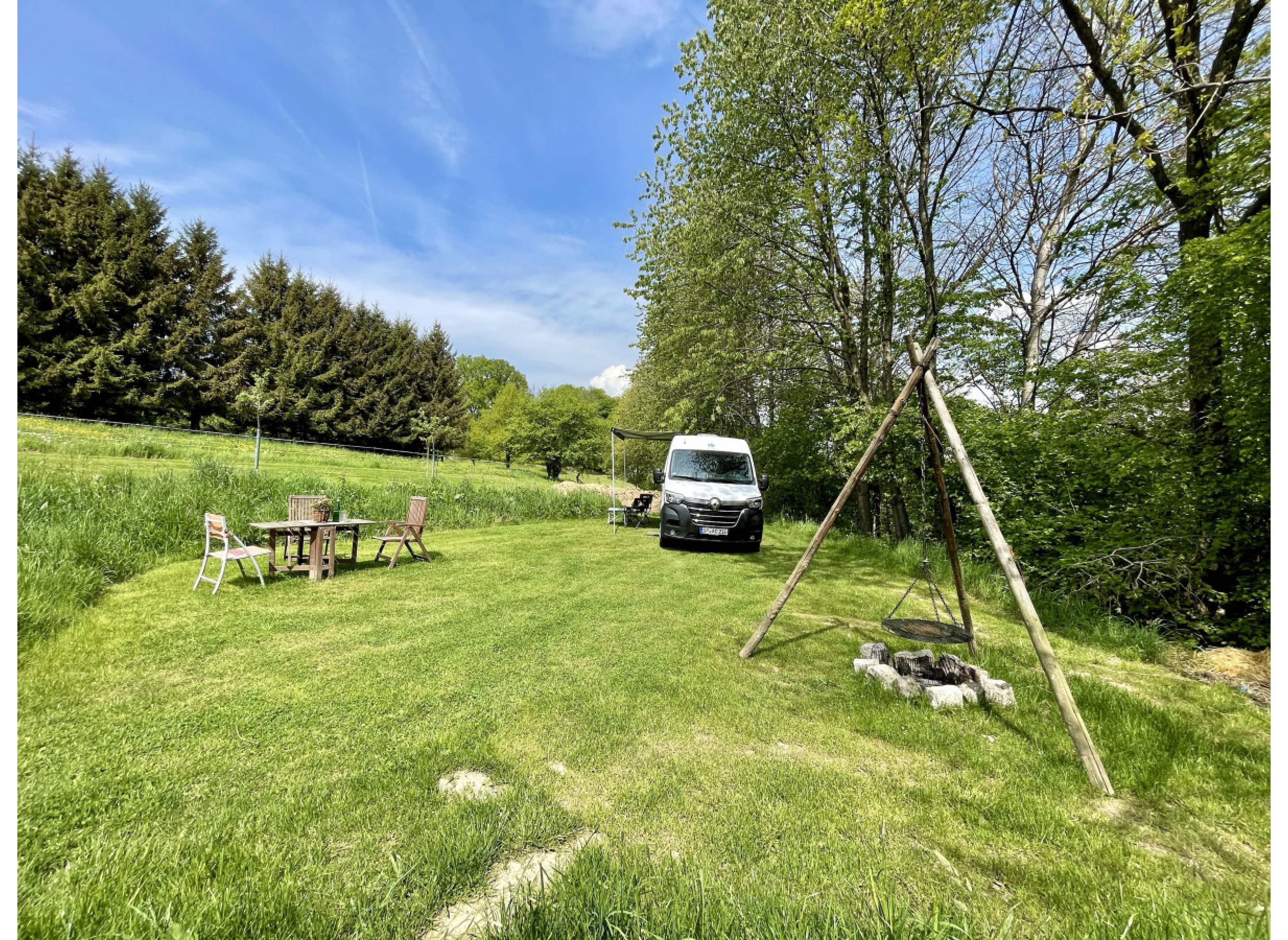 Wunderschöner Campingort auf einer saftig grünen Wiese neben einem Wald